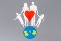 Earth Day. A felt-cut symbol of the planet earth and a red heart with paper silhouette of family. Gray background. Flat lay. Copy