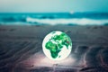 Earth globe glowing on the beach at night