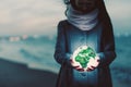 Earth globe glowing in woman`s hands on the beach at night