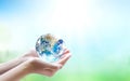 Human hands holding earth globe over blurred nature background. Elements of this image furnished by NASA Royalty Free Stock Photo