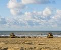 Earth movers working in their equipment machines at the beach for maintenance moving the sand Royalty Free Stock Photo