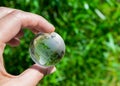 Crystal globe in the hand of a man against a background of green foliage. Earth protection concept. Earth Day Royalty Free Stock Photo