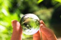 Crystal globe in the hand of a man against a background of green foliage. Earth protection concept. Earth Day Royalty Free Stock Photo