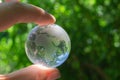 Crystal globe in the hand of a man against a background of green foliage. Earth protection concept. Earth Day Royalty Free Stock Photo