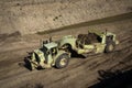 Earthmoving vehicles following each other while scrapping dirt as part of a grading project Royalty Free Stock Photo