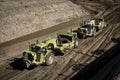 Earthmoving vehicles following each other while scrapping dirt  as part of a grading project Royalty Free Stock Photo