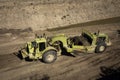 Earthmoving vehicles following each other while scrapping dirt Royalty Free Stock Photo