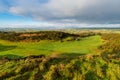 Eary morning light reveals a lush green golf course with a rolling landscape of grass and fields in Ireland