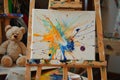 easel with abstract paint splotches, teddy bear nearby Royalty Free Stock Photo
