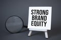 Easel,magnifier and STRONG BRAND EQUITY. Concept of success, growth and performance improvement. Statistics and business analytics Royalty Free Stock Photo