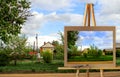 Easel with a painting watercolor rural landscape with village ga