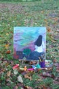 Easel with paints and painting on canvas in autumn park Royalty Free Stock Photo