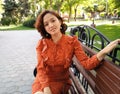 East Asian woman sitting on park bench smiling happy at camera. Pretty young japanese woman enjoying summer in park on parkbench Royalty Free Stock Photo