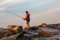 Fisher on the rock beach in East Greenwich, Rhode Island on sunset