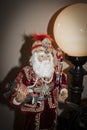East Indian Santa figure holding little elephant with headress and jeweled stick standing by large retro globe lamp - Christmas