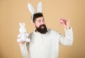 Easter activities concept. Weirdo concept. Celebrate Easter. Guy bearded hipster weird bunny with long white ears beige
