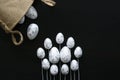 Easter arrangement. White eggs with silver details on sticks, and jute bag. Black background. Royalty Free Stock Photo