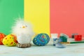 Easter baby chicken next to eggs on multicolor wooden background with paints and brush Royalty Free Stock Photo