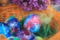 Easter background. Art decorated eggs with lilac and feather in basket