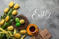 Easter background with blue, green eggs and a cup of tea in nest and yellow tulips. Top view with copy space Royalty Free Stock Photo