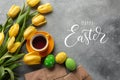 Easter background with blue, green eggs and a cup of tea in nest and yellow tulips. Top view with copy space Royalty Free Stock Photo