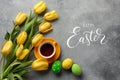 Easter background with blue, green eggs and a cup of tea in nest and yellow tulips. Top view with copy space Royalty Free Stock Photo