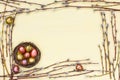 Easter background. Border of willow branch and quail eggs in small nest on yellow background. Copy space