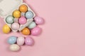 Easter background with a carton egg box with pastel colored easter eggs in and beside it on a pink background with space for copy