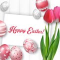 Easter background with colored eggs, red tulips and greeting card over white wood