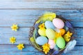 Easter background with colorful eggs in nest, feather and spring flowers top view. Holiday card or banner Royalty Free Stock Photo