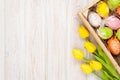 Easter background with colorful eggs and yellow tulips