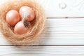 Easter background. Easter beige eggs and feather in nest on rustic white wooden background. Close-up, copy space