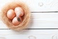 Easter background. Easter beige eggs and feather in nest on rustic white wooden background. Close-up, copy space Royalty Free Stock Photo