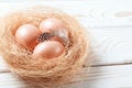 Easter background. Easter beige eggs and feather in nest on rustic white wooden background. Close-up, copy space Royalty Free Stock Photo