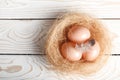 Easter background. Easter beige eggs and feather in nest on rustic white wooden background. Top view, copy space Royalty Free Stock Photo