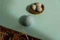 Easter egg on a blue background and and three small blue eggs in the nest