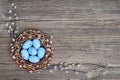 Easter background. Easter willow wreath and blue Easter eggs on old wooden background. Top view, copy space.