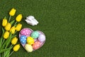 Easter background with eggs, buny and yellow tulips on a green grass