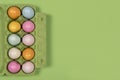 Easter background with a green carton egg box with pastel colored easter eggs in it on a green background with space for copy