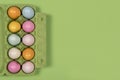Easter background with a green carton egg box with pastel colored easter eggs in it on a green background with space for copy Royalty Free Stock Photo
