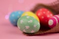 Easter background. Green, red and yellow painted eggs handmade in sackcloth on a pink background with bokeh. Royalty Free Stock Photo