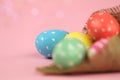 Easter background. Green, red and yellow painted eggs handmade in sackcloth on a pink background with bokeh. Royalty Free Stock Photo