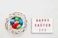 Easter background. HAPPY EASTER written in light box and colorful Easter eggs in wreath on light background. Top view, copy space Royalty Free Stock Photo