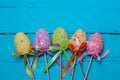 Easter background. Multicolored decorated easter eggs, multi-colored powder on a turquoise background. Free space