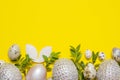 Easter background top view shining eggs and leaves on yellow