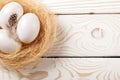 Easter background. Easter white eggs and feather in nest on rustic white wooden background. Top view, copy space Royalty Free Stock Photo