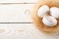 Easter background. Easter white eggs and feather in nest on rustic white wooden background. Top view, copy space Royalty Free Stock Photo