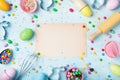 Easter baking background with paper card, rolling pin, whisk, decorative eggs, cookie cutters, candy and colorful confetti Royalty Free Stock Photo