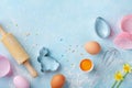 Easter baking background with rolling pin, whisk, eggs, flour and colorful confetti on blue table top view. Flat lay Royalty Free Stock Photo