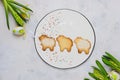 Easter baking, three lamb cookies made from shortcrust pastry with sugar on a white round ceramic board on a light concrete